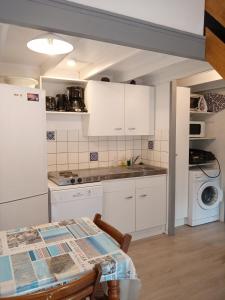 a kitchen with white cabinets and a table at A Deux Pas du Courant in Mimizan-Plage