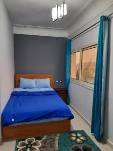 - une chambre avec un lit bleu et une fenêtre dans l'établissement Aton pyramids view guest house, au Caire