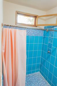 baño con cortina de ducha y azulejos azules en Hurvínek, en Montañita