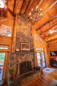 sala de estar con chimenea de piedra y TV en Luxe Log cabin with hot tub/spa/steam room!, en Wilmington