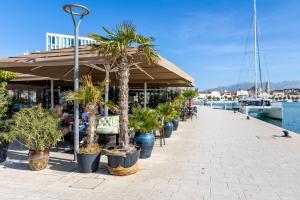 a boardwalk with palm trees inront of a restaurant at Marina Lux Split in Split