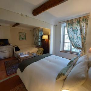 a bedroom with a large white bed and a living room at La Cordeline in Brignoles