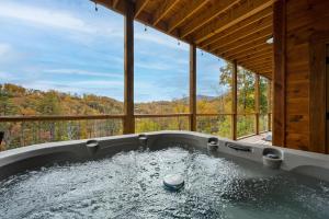 a jacuzzi tub with a view of the woods at The Overlook - '21 Cabin - Gorgeous Unobstructed Views - Fire Pit Table - GameRm - HotTub - Xbox - Lots of Bears in Gatlinburg