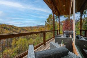 a balcony with chairs and a view of the woods at The Overlook - '21 Cabin - Gorgeous Unobstructed Views - Fire Pit Table - GameRm - HotTub - Xbox - Lots of Bears in Gatlinburg