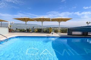 a swimming pool with umbrellas on top of a building at Kamaya Suites in Kinneret