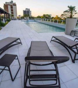 un patio con 2 mesas y sillas junto a una piscina en Sky Tower Increíble Departamento en Asunción, en Asunción