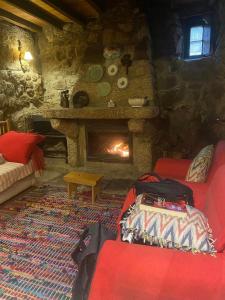 sala de estar con chimenea y sofá rojo en Casa das 5 Cruzes dentro da muralha, en Sortelha