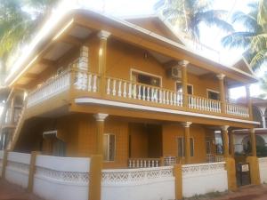 カンドリムにあるJason Guest Houseのバルコニー付きの大きな黄色の家