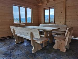 a wooden table and benches in a room with windows at Predlówka - Na dachu Świata in Zawoja