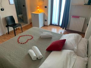 ポリニャーノ・ア・マーレにあるLe Dimore Del Sarto roomsの白と赤の枕とネックレス付きの白いベッド
