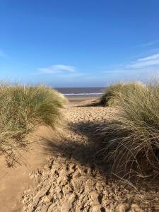 a sandy beach with tall grass and the ocean at The Cross Guest House in Mablethorpe
