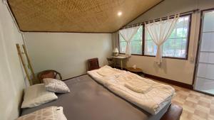 a bedroom with two beds in a room with windows at Brown House Chiangdao in Chiang Dao