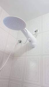 a shower head in a room with white cabinets at Casa na esquina da praia com quintal in Saquarema