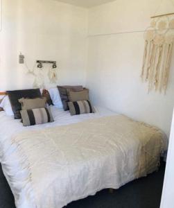 - une chambre avec un grand lit blanc et des oreillers dans l'établissement Un bol d'air à De Haan - Mer du Nord, au Coq