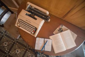 una vieja máquina de escribir sentada en una mesa con un libro en Casa D'aria, en Catania