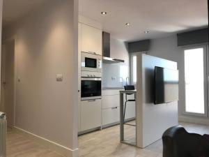 a kitchen with white cabinets and a microwave and a window at Albatros (wifi y garaje) in Ávila