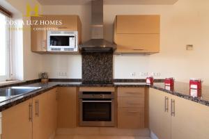 a kitchen with wooden cabinets and a stove top oven at Arcos Garden campo de golf fairway in Vallejas