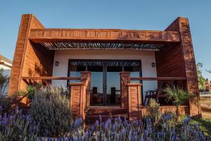 une maison avec une véranda ornée de fleurs violettes dans l'établissement Entrevalle Hotel Boutique, à Valle de Guadalupe