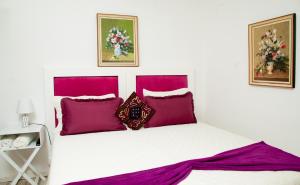 a bedroom with a white bed with purple pillows at Cozy Blue Guesthouse in East London