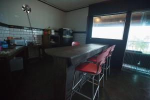 uma cozinha com um bar com bancos vermelhos em Curvão Surf House no Guarujá