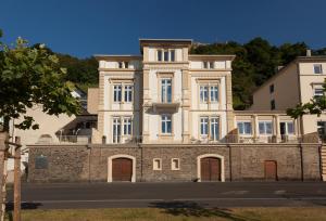 ein großes weißes Gebäude auf einer Steinmauer in der Unterkunft Ferienwohnungen Villa Mosella in Bernkastel-Kues