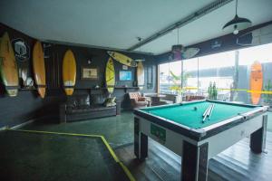a pool table in a room with surfboards on the wall at Curvão Surf House in Guarujá
