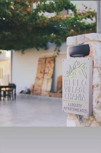 een bord op een stenen muur met een gebouw bij Hello Village Chania in SFakianalíon