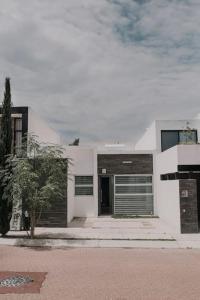 a white house with a door and a tree at Amazing House in Aguacalientes with Pool in Aguascalientes