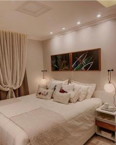 1 dormitorio con 1 cama blanca grande con almohadas blancas en Apartamento para temporada mobiliado en Alter do Chao