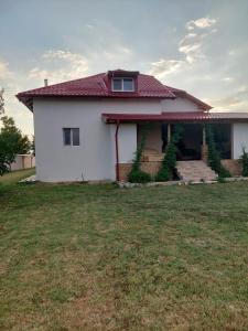 une maison blanche avec un toit rouge sur une cour dans l'établissement Cozy and modern house, à Udeni-Zăvoi