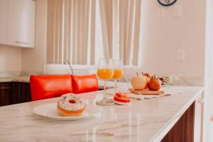 a kitchen counter with two glasses of orange juice and donuts at Hermosa Moderna Casa en Privada in Aguascalientes