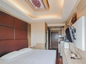 een slaapkamer met een wit bed en een televisie bij RedLiving Apartemen The Suites Metro - King Property Tower C in Bandung