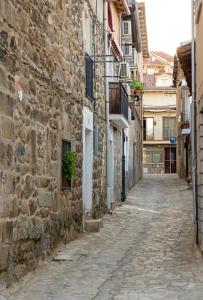 um beco numa cidade velha com edifícios de pedra em Casa Rural La Pinara em La Adrada