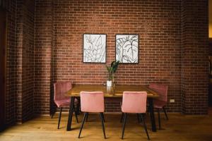 a table with pink chairs and a brick wall at Spacious Loft Over Coffee Shop - Romantic Downtown Escape in Greeley