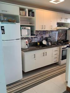 uma cozinha com armários brancos e um frigorífico branco em Itacimirim vilage Villas da Praia em Itacimirim