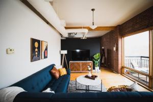 a living room with a blue couch and a large window at Spacious Loft Over Coffee Shop - Romantic Downtown Escape in Greeley