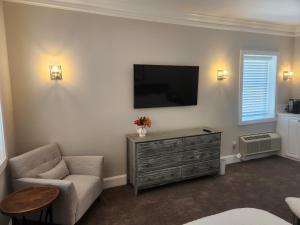 a living room with a tv and a chair and a dresser at Capital Hotel Annapolis in Annapolis