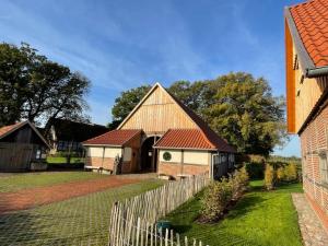 a barn with a fence next to a house at Artlandhaus 1719 - Geschichte trifft Moderne in Menslage