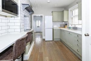 eine Küche mit weißen Schränken und einem weißen Kühlschrank in der Unterkunft Lovely 2-bedroom maisonette in Windsor in Windsor