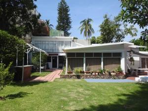 une maison blanche avec une pelouse devant elle dans l'établissement Habitación independiente a pie del lago con AC, à Tequesquitengo