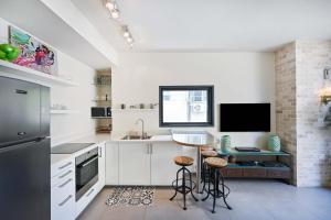 a kitchen with white cabinets and a table and a tv at Hess st close to the beach by HolyGuest in Tel Aviv
