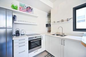 a white kitchen with white cabinets and a sink at Hess st close to the beach by HolyGuest in Tel Aviv