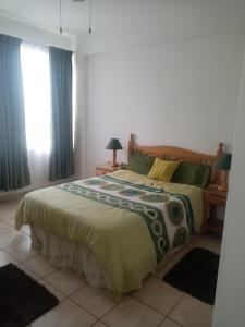 a bedroom with a bed with a green and white comforter at Happy days in Amanzimtoti