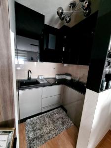 - une cuisine avec des placards noirs et blancs et un tapis dans l'établissement Vip apartman Zlatiborski konak, à Zlatibor