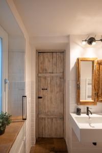 ein Badezimmer mit einer Holztür, einem Waschbecken und einem Spiegel in der Unterkunft La Rosa del Borgo in Ancona