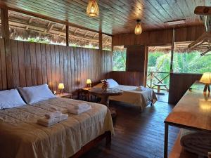 1 dormitorio con 2 camas y 2 mesas. en Sotupa Eco Lodge en Puerto Maldonado