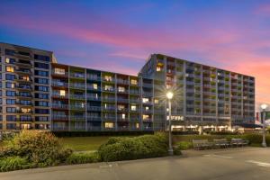 a large apartment building with a parking lot at dusk at Sandcastle Resort in Virginia Beach