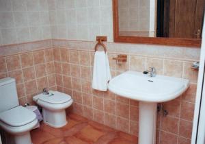 een badkamer met een wastafel, een toilet en een spiegel bij Pensión Restaurante Venta El Molino in Sopalmo