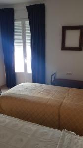 a bedroom with a bed with blue curtains and a window at Casa Lavanderas in Algodonales