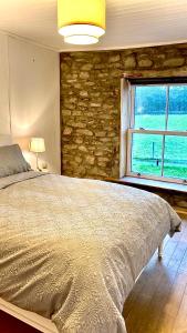 a bedroom with a large bed and a stone wall at Dove Cottage in Newbridge on Wye